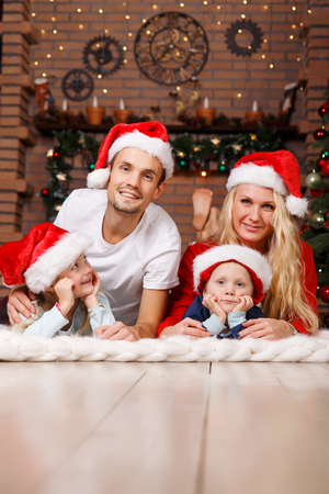 Married couple with two children on soft plaid in Christmas treeの写真素材