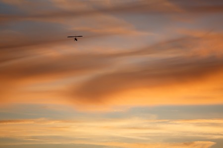 Red sky with hang glider flying in cloudsの写真素材