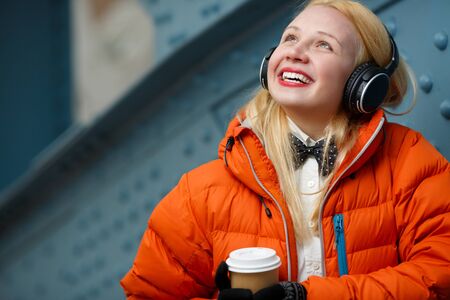 Happy girl in orange jacket on background of blue wallの写真素材