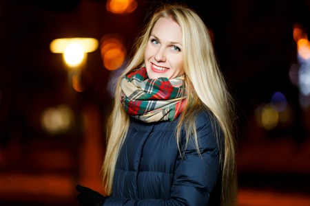 Festive girl in winter tree on street at nightの写真素材