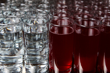 Glasses of water and red beverage on blank against black backgroundの写真素材