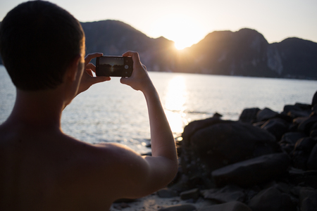 Young guy photographes on beach,の写真素材
