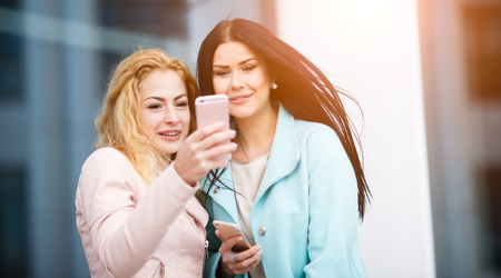 Two beautiful women with phoneの写真素材