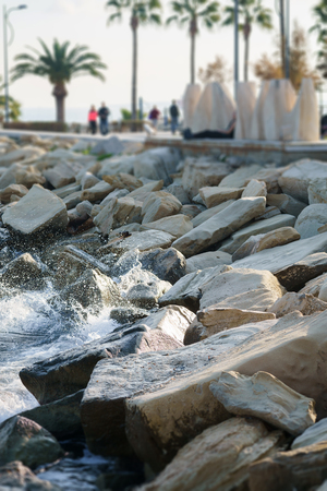 Photo of sea shore, stones, palms and touristsの写真素材