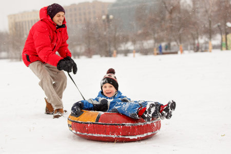 Photo of cheerful father skating son on winter