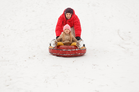 Photo of father and daughter on walk with tubing in winter parkの写真素材