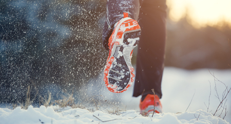 Image from back of running man in sneakers in sports clothes on snowの写真素材