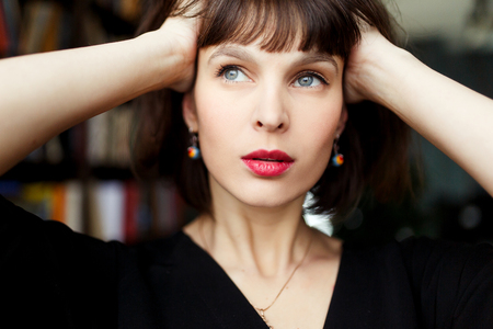 Brunette in black dress on background of booksの写真素材