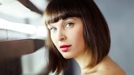Photo of young brunette in black dress near window with blinds in studioの写真素材