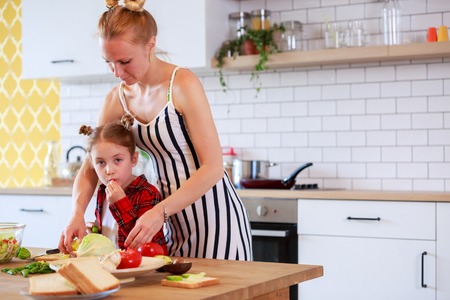 Picture of young mother with her daughter cutting vegetables in kitchenの写真素材