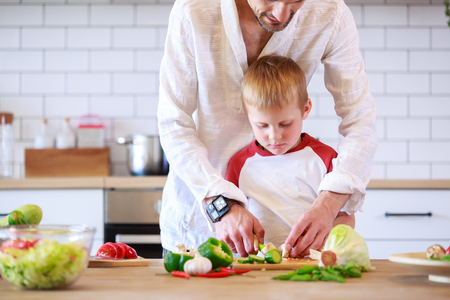 Photo of man and his son preparing food at table with vegetablesの写真素材