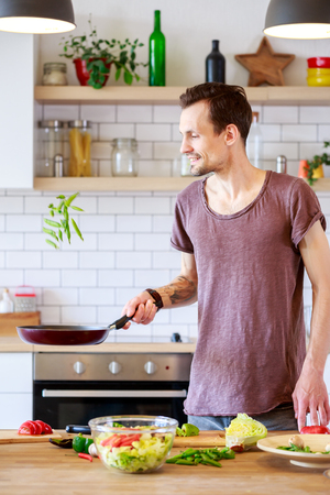 Picture of man with frying pan in hands in kitchenの写真素材