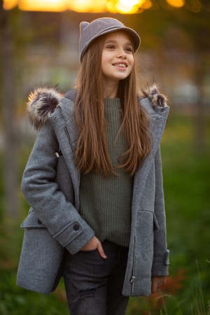 Photo of girl in gray hat and coat on blurred background at cityの写真素材