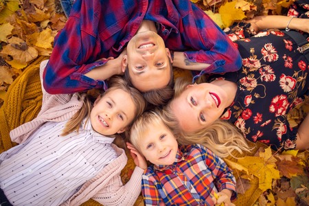 Photo from above of lying parents with children on yellow leaves in parkの写真素材