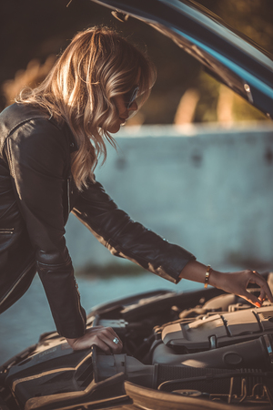 Photo of side of young woman near broken car with open hoodの写真素材