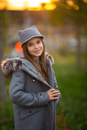 Photo of girl in gray hat and coat on blurred background at cityの写真素材