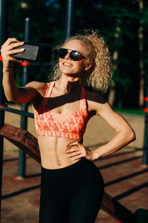 Photo of smiling sports woman wearing sunglasses doing selfie inの写真素材