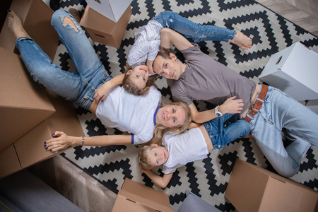 Picture from above of women, men and children lying on floor among cardboard boxesの写真素材