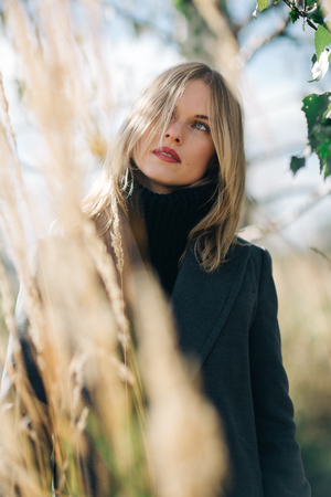 Photo of young woman looking up on blurred background of treeの写真素材