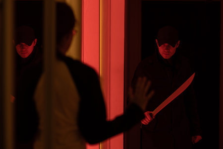 Photo of thief with machete and man with hands up in dark room