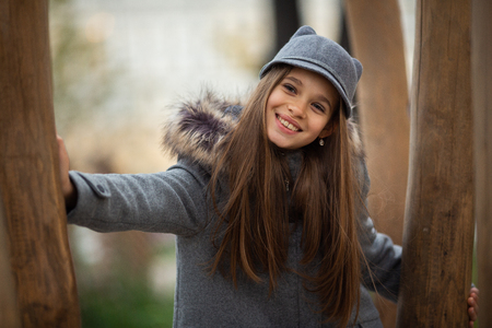 Photo of girl in gray hat and coat among trees on blurred backgroundの写真素材