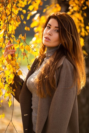 Portrait of young long-haired brunette in autumn forestの写真素材