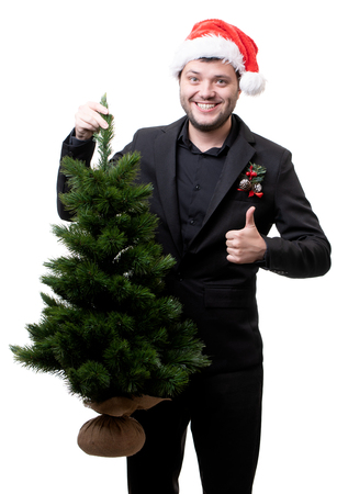 Photo of happy man in Santa hat with Christmas treeの写真素材