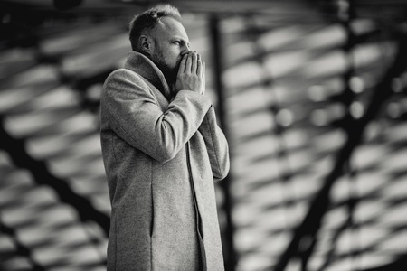 Black and white image under film of serious man in coat under glass roofの写真素材