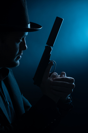 Photo of side of man in black hat with pistolの写真素材