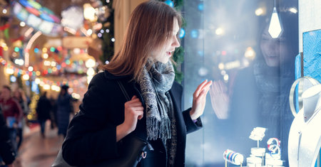 Photo side of young brunette at shop window in evening