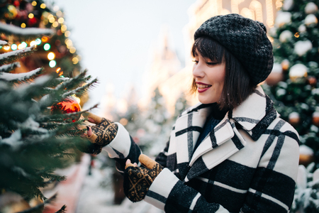 Photo of young brunette near painted Christmas tree on streetの写真素材