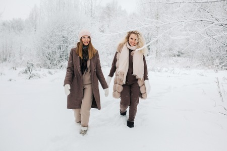 Portrait of two blonde women in hat on walk in winter forestの写真素材