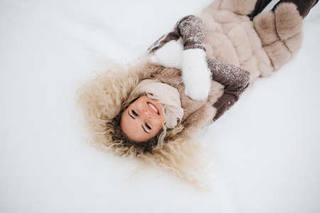 Photo of blonde lying in snow on walkの写真素材