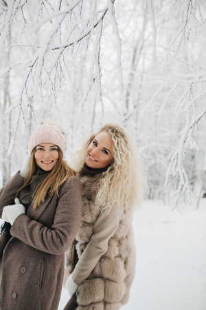 Photo of two blonde women on walk in winter forestの写真素材