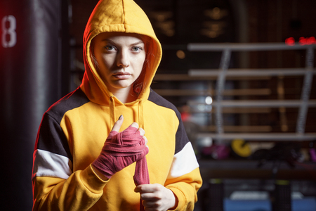 Female boxer pulls red bandages around her hands on ring.の写真素材
