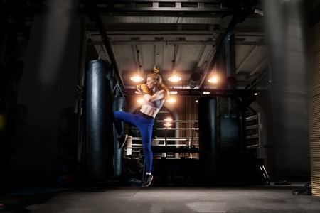 Woman boxer practicing near bag, ring in gym.の写真素材