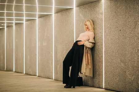 Blonde in coat and black pants in underpass.の写真素材