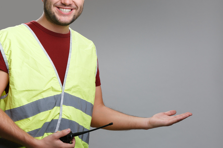 Photo of smiling builder in yellow vest with raised palm upの写真素材