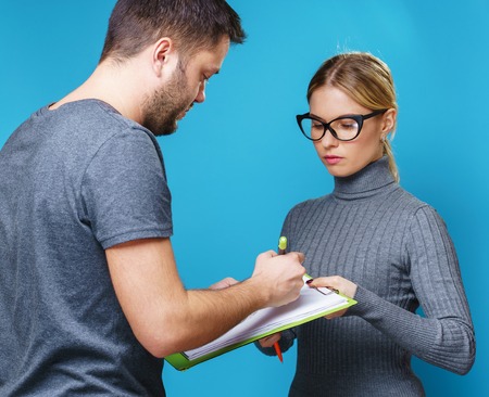 Photo of woman in glasses with notebook in hand and man from backの写真素材