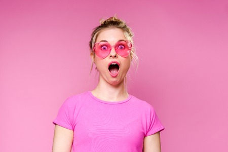 Photo of surprised blonde in pink T-shirtの写真素材