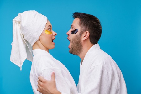 Image on side of man and woman with gel pads under eyes and in white robeの写真素材