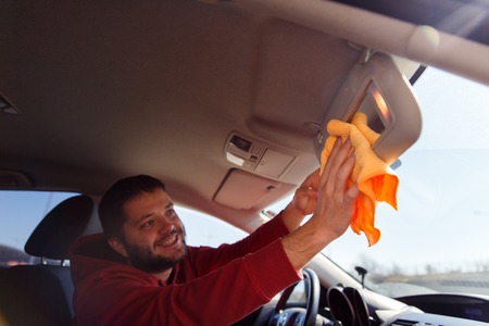 Photo on side of happy male with orange rag washing mirror of carの写真素材