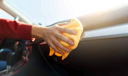 Photo of human hand with orange cloth washing machine interior, close-up.の写真素材