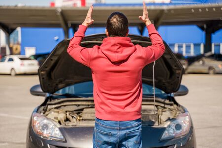 Image on back of man next to open hood of broken car in daytimeの写真素材