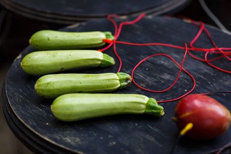 Photo of zucchini, avocado with red wires on black tableの写真素材