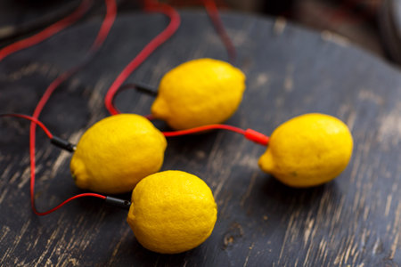 Photo of lemons with red wires on black wooden table