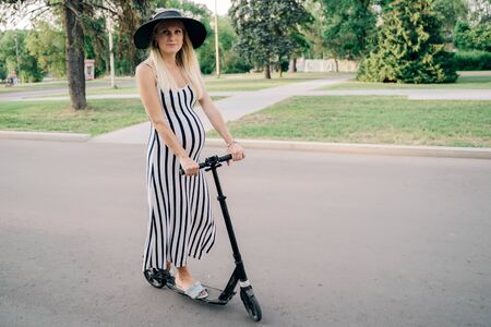 Photo of pregnant woman on scooter in parkの写真素材