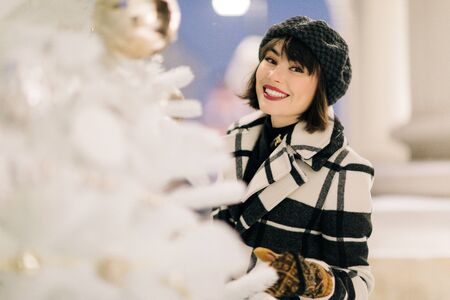 Image of happy woman near white artificial Christmas tree on walk at streetの写真素材