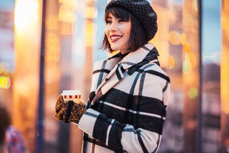 Picture of happy brunette with glass in her hands on walk on streetの写真素材