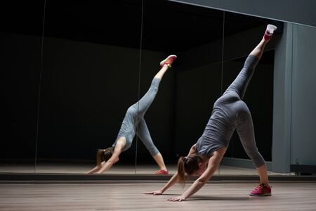 Young athletic brunette in gray sports suit in stretching trainingの写真素材